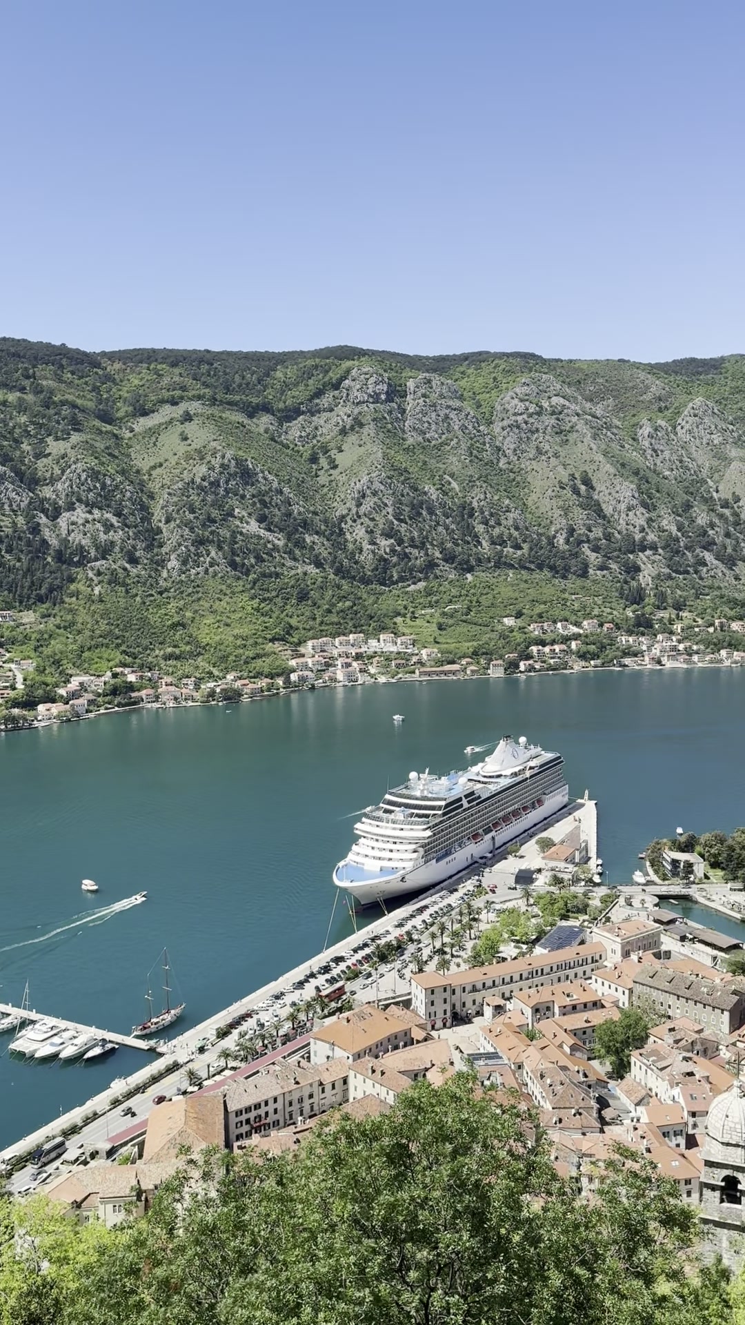 A cruise ship docked beside Kotor old town below the fortress walls
