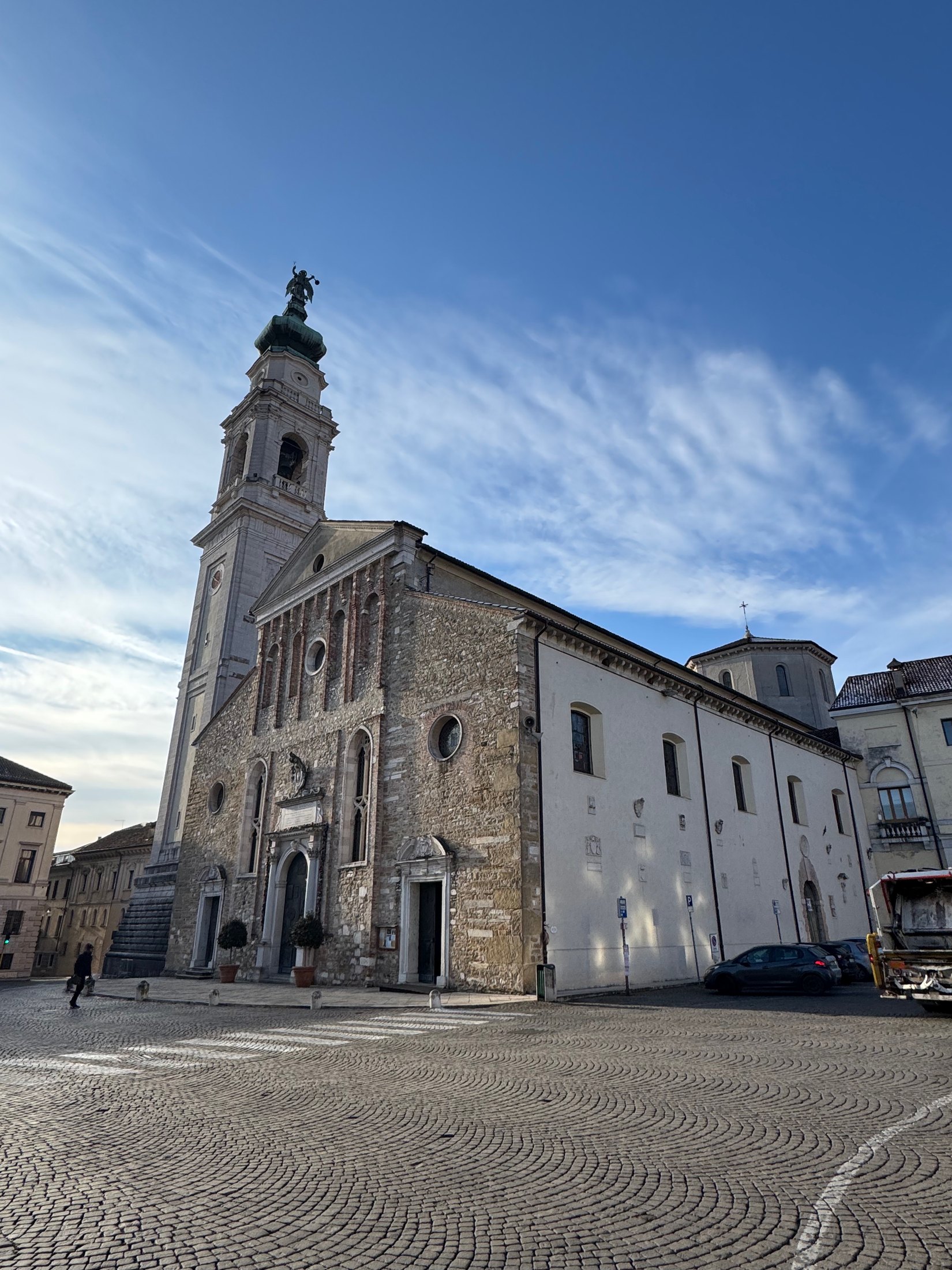 Belluno church and old-town stone square below a blue sky.