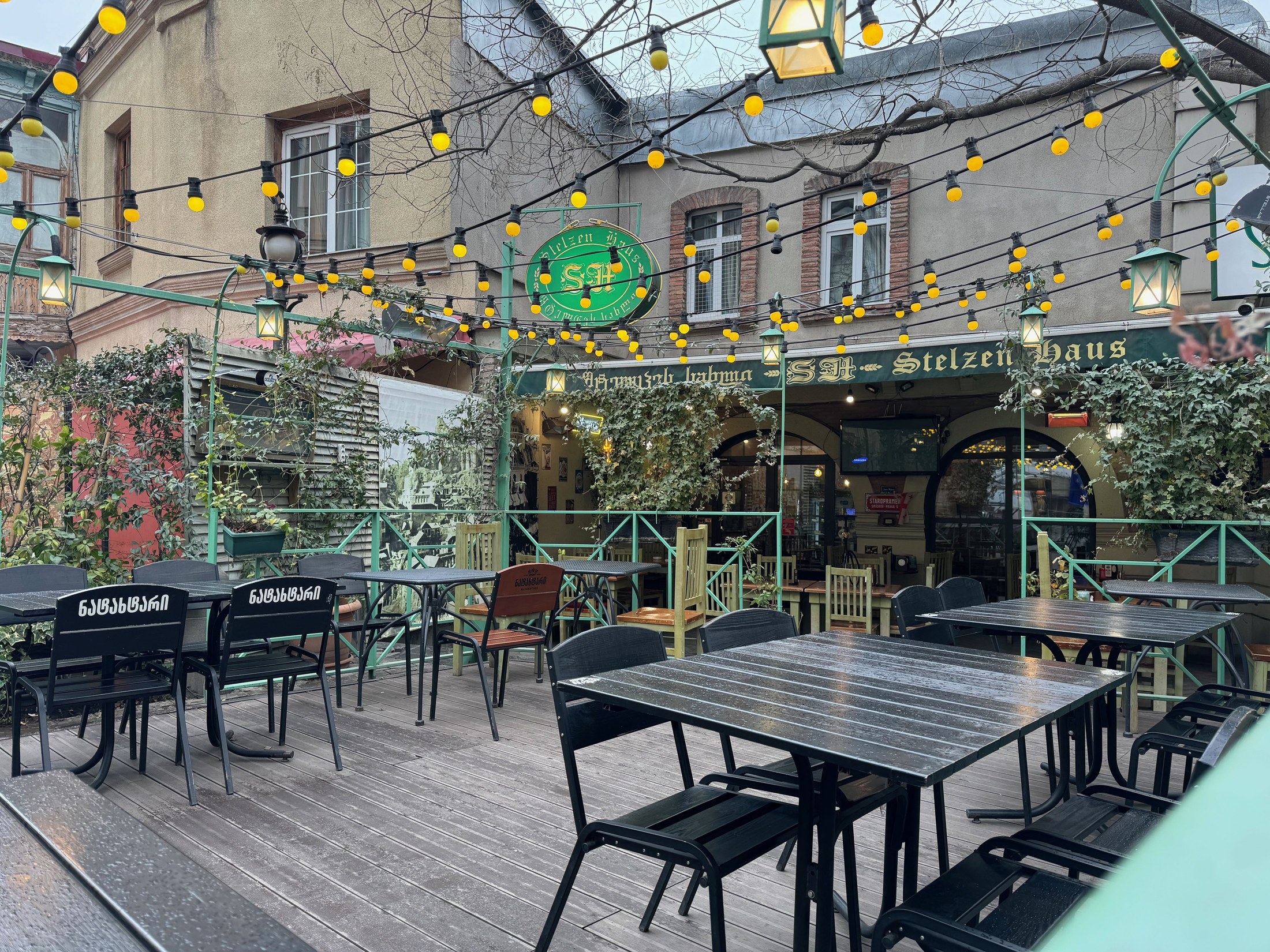 Empty patio tables under yellow string lights at Seven Roads in Tbilisi