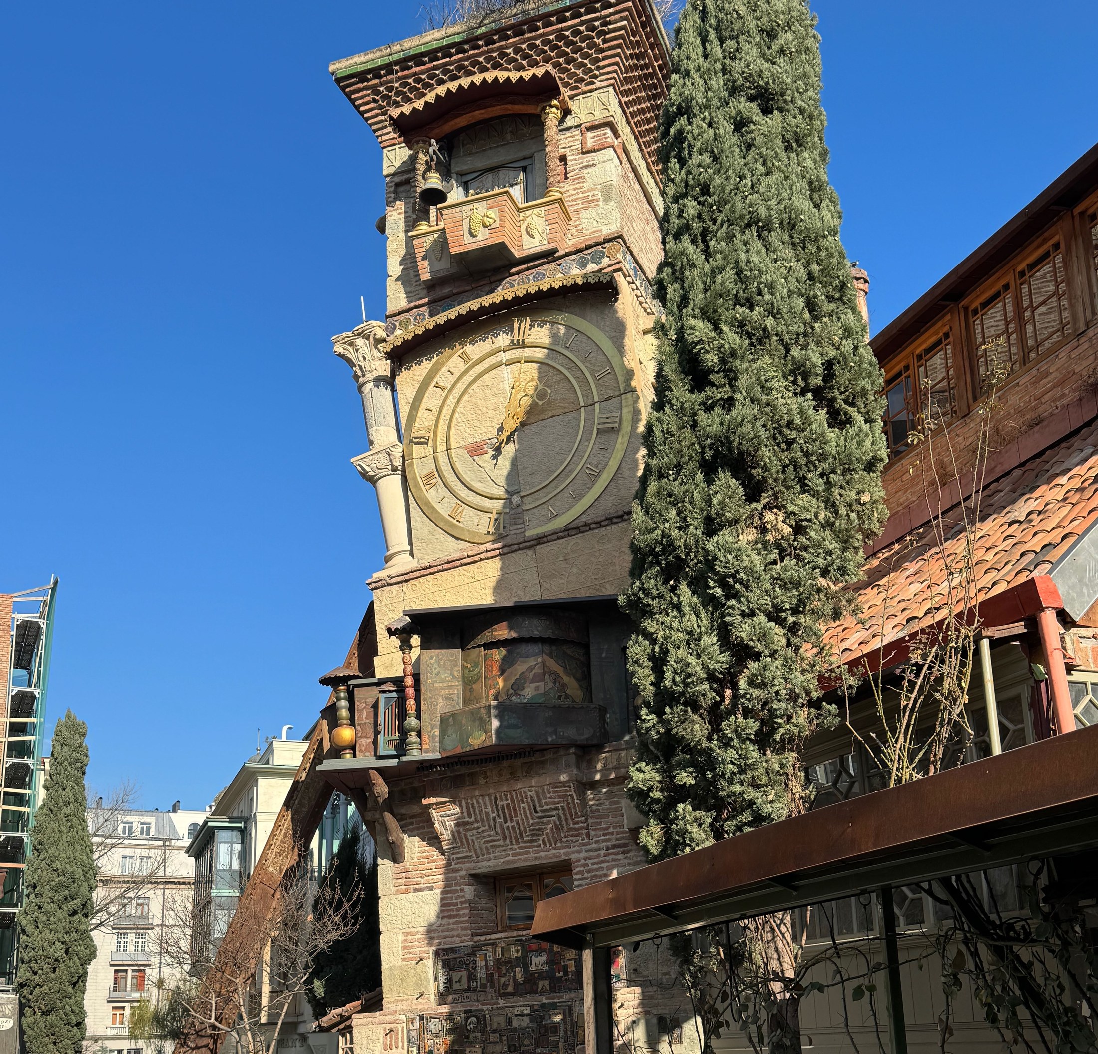 The leaning clock tower in Tbilisi old town under a blue sky