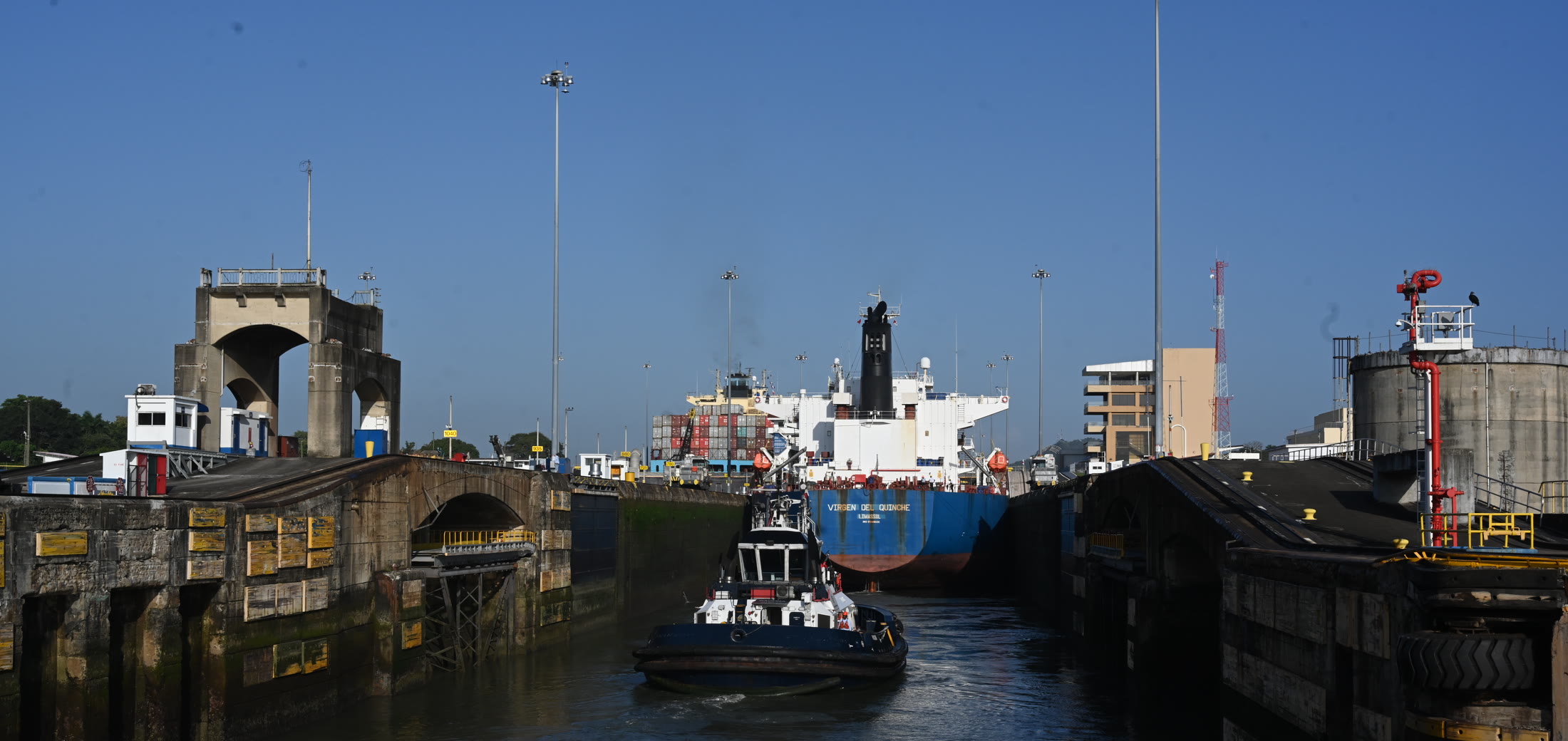 A cargo ship and tug moving through the Panama Canal locks