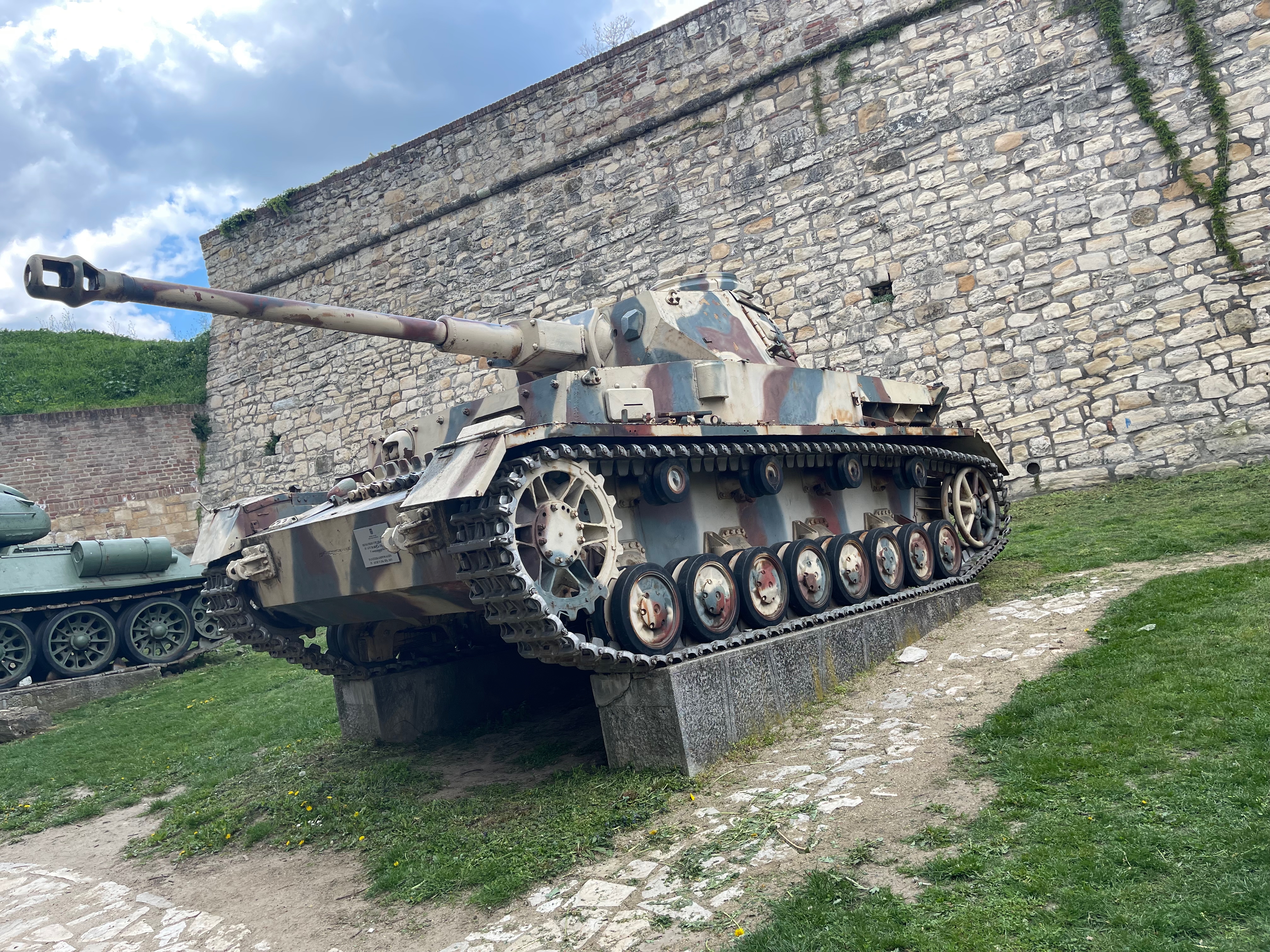 A tank on display against the stone fortress wall at Belgrade's Military Museum